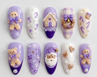 May include: A set of ten press-on nails featuring festive holiday designs in shades of purple, white, and cream. Decorations include 3D gingerbread figures, a gingerbread house, a Santa Claus face, a wreath, teddy bears, candy canes, and snowflakes.