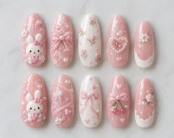 May include: A set of ten almond-shaped press-on nails featuring a pink and white color palette. Designs include 3D white rabbits, pink bows, cherry charms, pearl accents, floral patterns, heart shapes, and plaid textures with glossy finishes.
