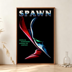 Könnte beinhalten: Ein gerahmtes Poster mit dem Wort SPAWN in weißer und blauer Schrift am oberen Rand. Das Bild zeigt eine dunkle, schattenhafte Figur mit einem leuchtend grünen Auge und einem wehenden roten Umhang. Der Text BORN IN DARKNESS SWORN TO JUSTICE ist grün.