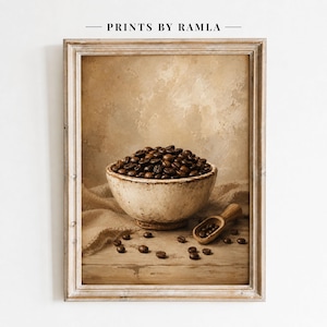 May include: A framed wall art print titled PRINTS BY RAMLA featuring a rustic off-white ceramic bowl filled with dark roasted coffee beans. A small wooden scoop rests nearby on a wooden surface, with several loose coffee beans scattered around.