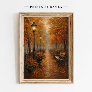 Peut inclure: Une impression d'art encadrée intitulée PRINTS BY RAMLA représentant un parc en automne avec un chemin pavé, des lampadaires noirs éclairés, des arbres aux tons orange et jaune, et un banc en bois. Le sol est jonché de feuilles mortes.