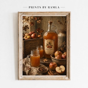 Può includere: Una stampa artistica incorniciata intitolata PRINTS BY RAMLA raffigurante una caraffa di vetro di sidro di mele, due boccali di vetro pieni di sidro, una cassa di legno con l'etichetta ORCHARDS, mele rosse fresche e bastoncini di cannella.