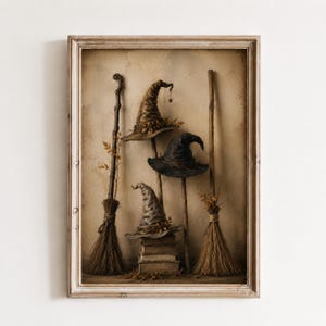 Puede incluir: Una impresión de arte mural enmarcada que muestra tres sombreros puntiagudos en tonos marrón, negro y gris, cada uno adornado con pequeñas hojas. Dos escobas de madera se alzan verticalmente a los lados, mientras los sombreros descansan sobre tres libros.