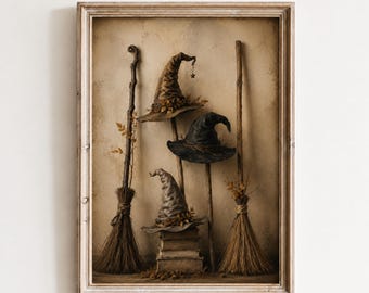 May include: A framed wall art print featuring three pointed hats in shades of brown, black, and gray, each adorned with small leaves. Two wooden broomsticks stand vertically on either side, while the hats rest atop a stack of three books.