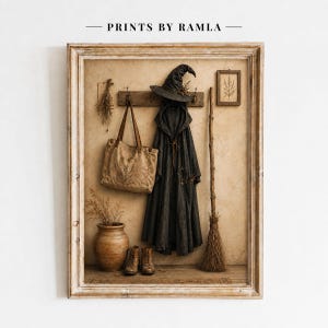 Könnte beinhalten: Ein gerahmter Kunstdruck mit dem Titel PRINTS BY RAMLA, der einen dunklen Umhang mit Kapuze, einen spitzen Hut, eine Stofftasche, einen Besen und ein Paar Stiefel an einer Holzhakenleiste zeigt. Ein Keramikgefäß mit getrockneten Pflanzen steht darunter.