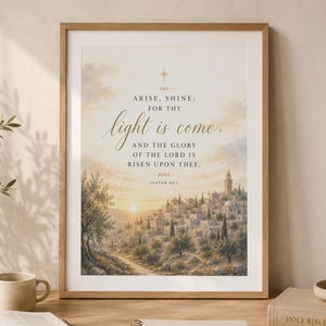 Puede incluir: Una lámina artística enmarcada con una ilustración paisajística de una ciudad en la ladera al amanecer. El texto dice: ARISE, SHINE; FOR THY light is come, AND THE GLORY OF THE LORD IS RISEN UPON THEE. ISAIAH 60:1. El marco es de madera clara.