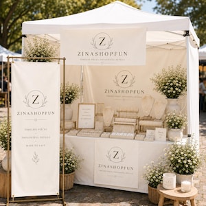 May include: A white pop-up market stall featuring the ZINASHOPFUN logo with a letter Z inside a circle. The booth displays jewellery on stands, white banners with text, and potted white flowers in woven baskets on a wooden stool and the ground.