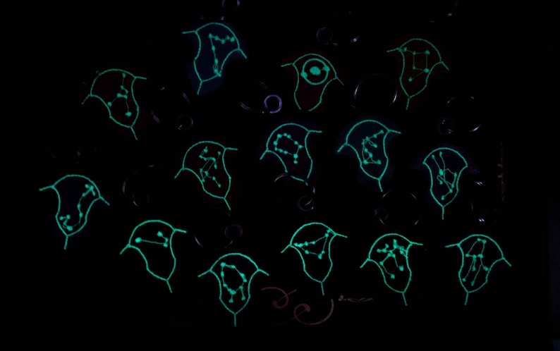 K&ouml;nnte beinhalten: Eine Sammlung von vierzehn einzelnen, glockenf&ouml;rmigen Symbolen, die in einem Raster vor einem schwarzen Hintergrund angeordnet sind. Jedes Symbol zeigt ein einzigartiges, leuchtend hellblaues Sternbildmuster aus Punkten und Linien.