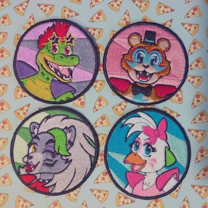 Puede incluir: Cuatro parches redondos bordados con personajes de dibujos animados coloridos. Los personajes incluyen un caimán verde, un oso pardo, un lobo gris y un pato blanco, cada uno con detalles distintivos.