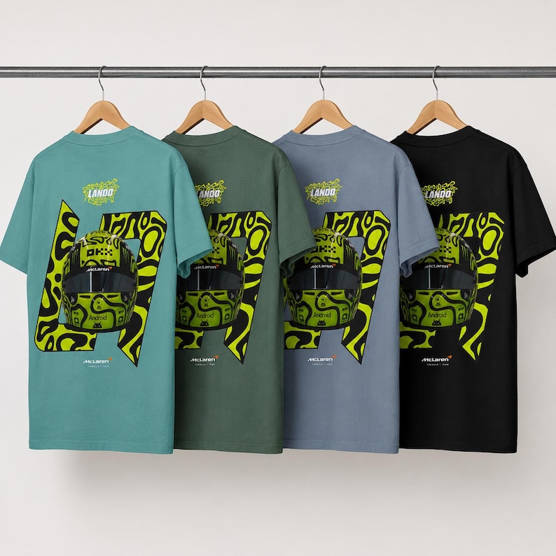 May include: Four short-sleeve t-shirts in teal, olive green, slate blue, and black hanging on hangers. Each shirt features a graphic of a yellow and black racing helmet, the number 47, the text LANDO, and the McLaren logo on the back.