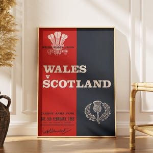 Könnte beinhalten: Ein vertikales rechteckiges Poster mit einem zweigeteilten Hintergrund in Rot und Dunkelblau. Der Text lautet WALES v SCOTLAND, CARDIFF ARMS PARK, SAT. 5th FEBRUARY, 1966. Es enthält das Emblem der Welsh Rugby Union, eine Distel und eine Signatur.