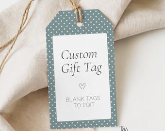 Puede incluir: Una etiqueta de regalo rectangular con fondo azul polvoriento, patrón de puntos blancos y un rectángulo blanco central. El texto dice Custom Gift Tag, un icono de corazón pequeño y BLANK TAGS TO EDIT. Un cordel marrón está atado en la parte superior.
