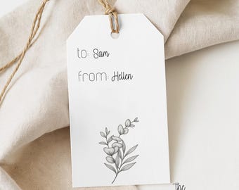 Puede incluir: Una etiqueta de regalo rectangular blanca con un agujero en la parte superior y un cordel marrón. La etiqueta presenta el texto impreso en negro "to: Sam" y "from: Hellen" sobre una detallada ilustración botánica en blanco y negro.