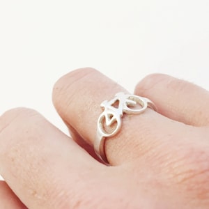 Puede incluir: Un anillo de plata con forma de bicicleta en un dedo.