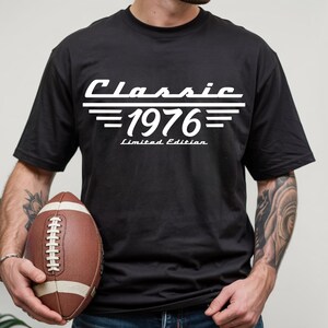 May include: A black short-sleeved t-shirt featuring white graphic text that reads Classic 1976 Limited Edition. The design includes horizontal lines above and below the year 1976, centered on the chest of the garment.