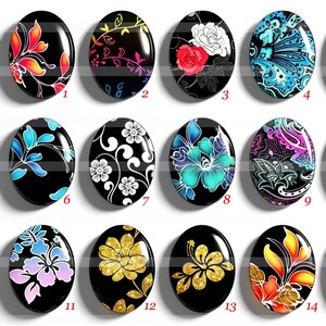 Op de afbeelding: Een collectie van vijfentwintig ovale cabochons gerangschikt in een raster, elk met een uniek bloemen- of abstract patroon op een zwarte achtergrond. De ontwerpen bevatten levendige rode, blauwe, gouden en witte motieven, genummerd van één tot vijfentwintig.