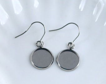 Può includere: Un paio di basi per orecchini in argento con cabochon rotondi in vetro trasparente. Gli orecchini hanno un design semplice ed elegante e sono perfetti per aggiungere il tuo tocco personale.