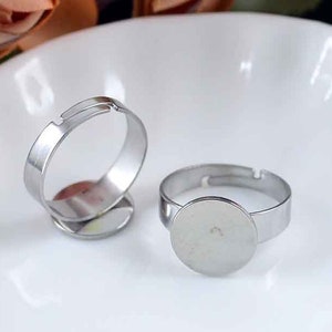 Puede incluir: Dos blancos de anillo ajustables de plata con biseles redondos. Los biseles son lisos y tienen un acabado brillante.