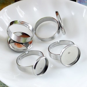 Puede incluir: Cinco bases de anillo plateadas con biseles redondos para engastar cabujones. Los biseles tienen un diámetro de aproximadamente 2,5 cm.