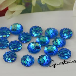 May include: Assortment of blue iridescent round cabochons with a scale pattern. The cabochons are approximately 10mm in diameter.