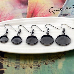 May include: Five pairs of black metal earring blanks with round, empty, silver-toned bezels. The bezels are different sizes.