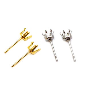 May include: Two pairs of earring settings, one pair is gold and the other is silver. Each setting has a crown-shaped top with six prongs to hold a gemstone.