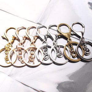 Puede incluir: Un juego de seis llaveros con diferentes acabados, incluyendo plata, oro y bronce. Cada llavero tiene un anillo doble y un cierre giratorio.