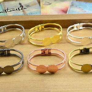 May include: Six double-layered bangle bracelets with a magnetic clasp. Each bracelet has two round, flat, metal circles on the front. The bracelets are in silver, gold, rose gold, and black.