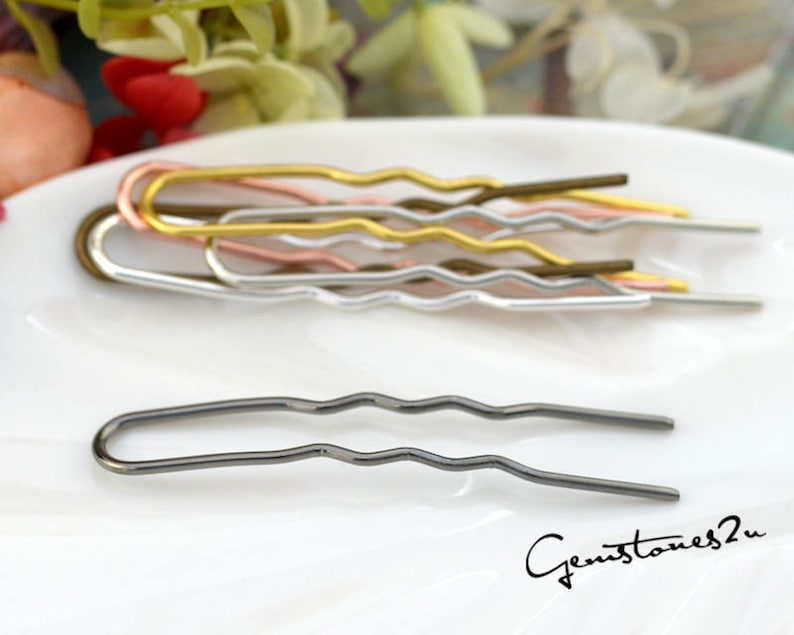 May include: A set of five wavy hair pins in different metallic colors: gold, rose gold, silver, and black. The pins are arranged in a row on a white surface.