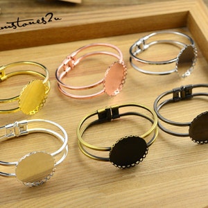 May include: Six double-layered bangle bracelets with a round, scalloped bezel setting. The bezels are in gold, silver, rose gold, and black.