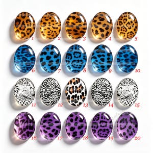 May include: Twenty oval-shaped glass cabochons arranged in four rows of five. The designs feature various leopard print patterns in orange, blue, black and white, and purple. Each cabochon is numbered from 1 to 20 in red text next to the item.