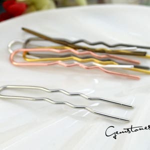 May include: A set of five wavy hair pins in silver, gold, rose gold, and black. The pins are arranged on a white surface.