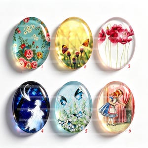 Può includere: Sei cabochon ovali in vetro con distinti disegni stampati: un motivo floreale, farfalle in luce dorata, papaveri rossi, una figura sagomata in una foresta scura, farfalle blu in un prato e una ragazza in abito vicino a tende rosse.