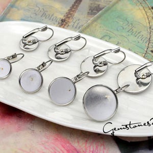 Peut inclure: Sept montures de boucles d'oreilles argentées avec des cabochons en verre transparent. Les montures ont une fermeture à levier.