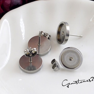 May include: Three silver earring settings with round bezels. The bezels are designed to hold a cabochon stone.