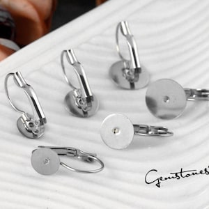 May include: Five silver earring backs with a round, flat surface and a small hole in the center. The earring backs are designed to be used with clip-on earrings.