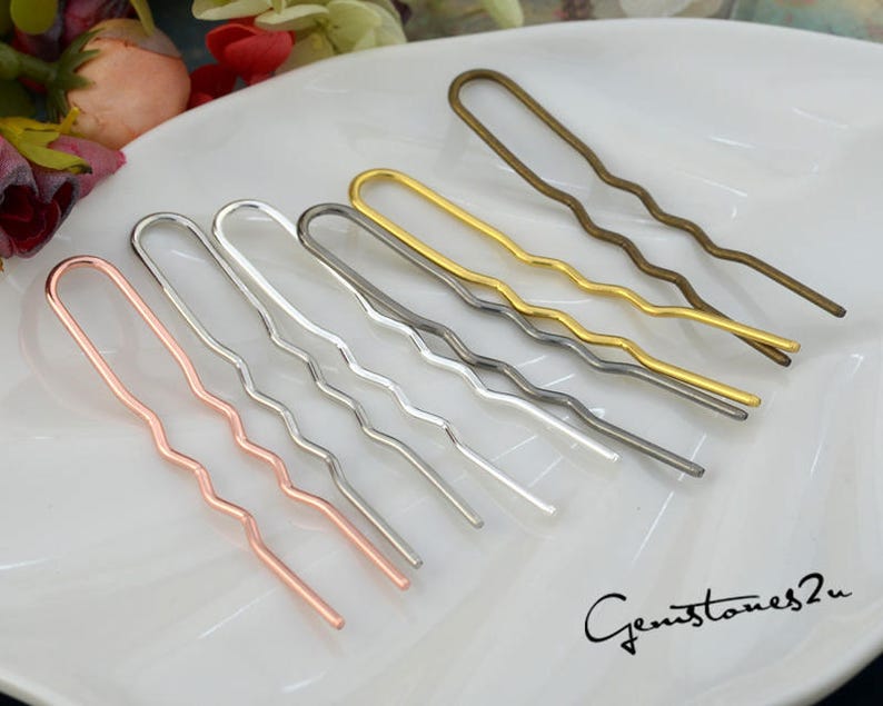 May include: A set of seven wavy hair pins in different metallic finishes, including gold, silver, bronze, and rose gold. The pins are arranged on a white surface.