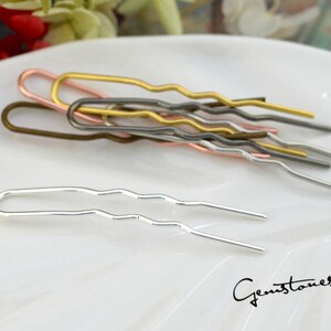 May include: A set of six wavy hair pins in silver, gold, rose gold, and bronze. The pins are arranged on a white surface.