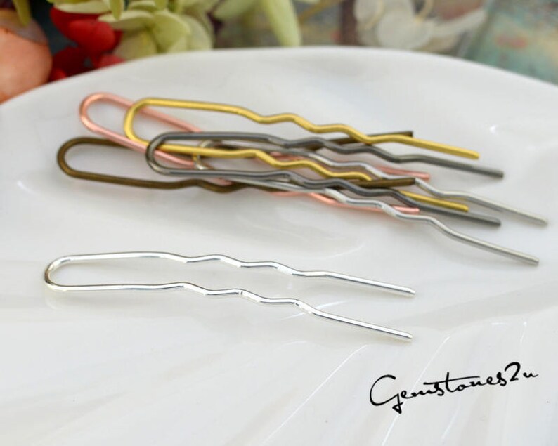 May include: A set of six wavy hair pins in silver, gold, rose gold, and bronze. The pins are arranged on a white surface.