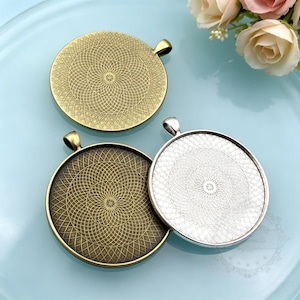 May include: Three circular pendant trays featuring a detailed geometric mandala-style pattern etched into the metal. The set includes one antique brass finish, one dark bronze finish, and one bright silver finish, each with a small top loop.