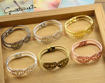 May include: Six different coloured metal bracelets with a delicate filigree design. The bracelets are displayed on a wooden surface.