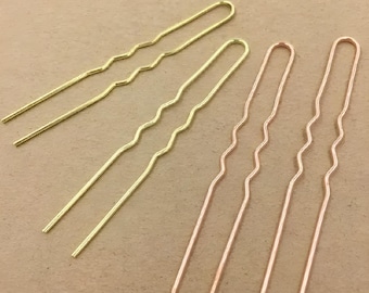 Puede incluir: Cuatro horquillas para el pelo, dos doradas y dos de oro rosa, con un diseño ondulado. Las horquillas están dispuestas en forma de abanico.