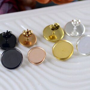 Può includere: Sei montature per orecchini con diverse finiture metalliche. Le montature sono rotonde e hanno una superficie piatta per fissare un cabochon. Le montature sono argentate, dorate, nere, oro rosa e due altre montature dorate.