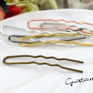 May include: A set of four wavy hair pins in silver, gold, rose gold, and bronze.