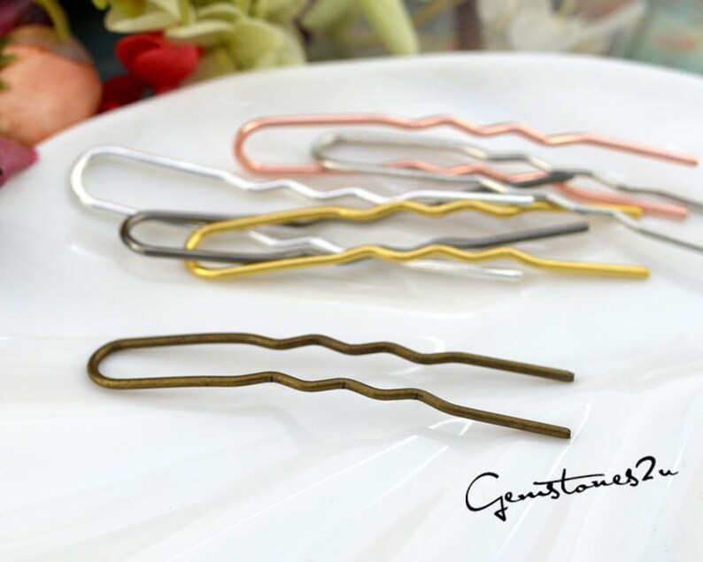 May include: A set of four wavy hair pins in silver, gold, rose gold, and bronze.