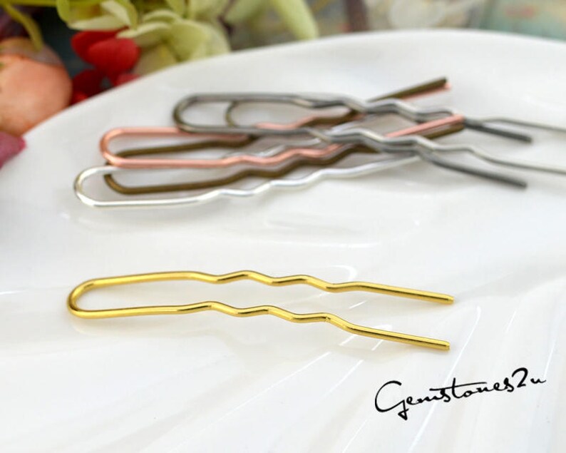 May include: A set of five gold, silver, and copper hair clips with a wavy design. The clips are arranged on a white surface.