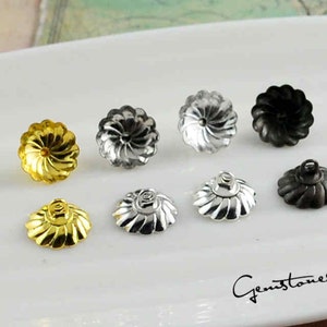 Puede incluir: Una variedad de ocho cierres de pendientes metálicos en oro, plata y negro. Los cierres de los pendientes tienen un diseño floral con un centro en espiral. La imagen está sobre una superficie blanca. El texto "Gemstones2u" está en la esquina inferior derecha.