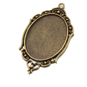 May include: An oval-shaped metal pendant with an ornate design. The pendant has a smooth, slightly textured surface and is a bronze color.
