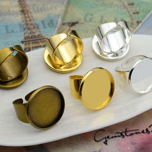 May include: Six different styles of metal ring blanks with a round bezel for setting stones or other materials. The blanks are in various colors, including gold, silver, and bronze.