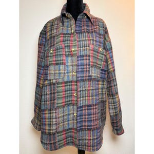 May include: A long-sleeved button-down shirt featuring a multi-colored plaid pattern in shades of blue, red, green, and yellow. The shirt includes a pointed collar, two chest pockets, and gold-toned buttons running down the front placket.